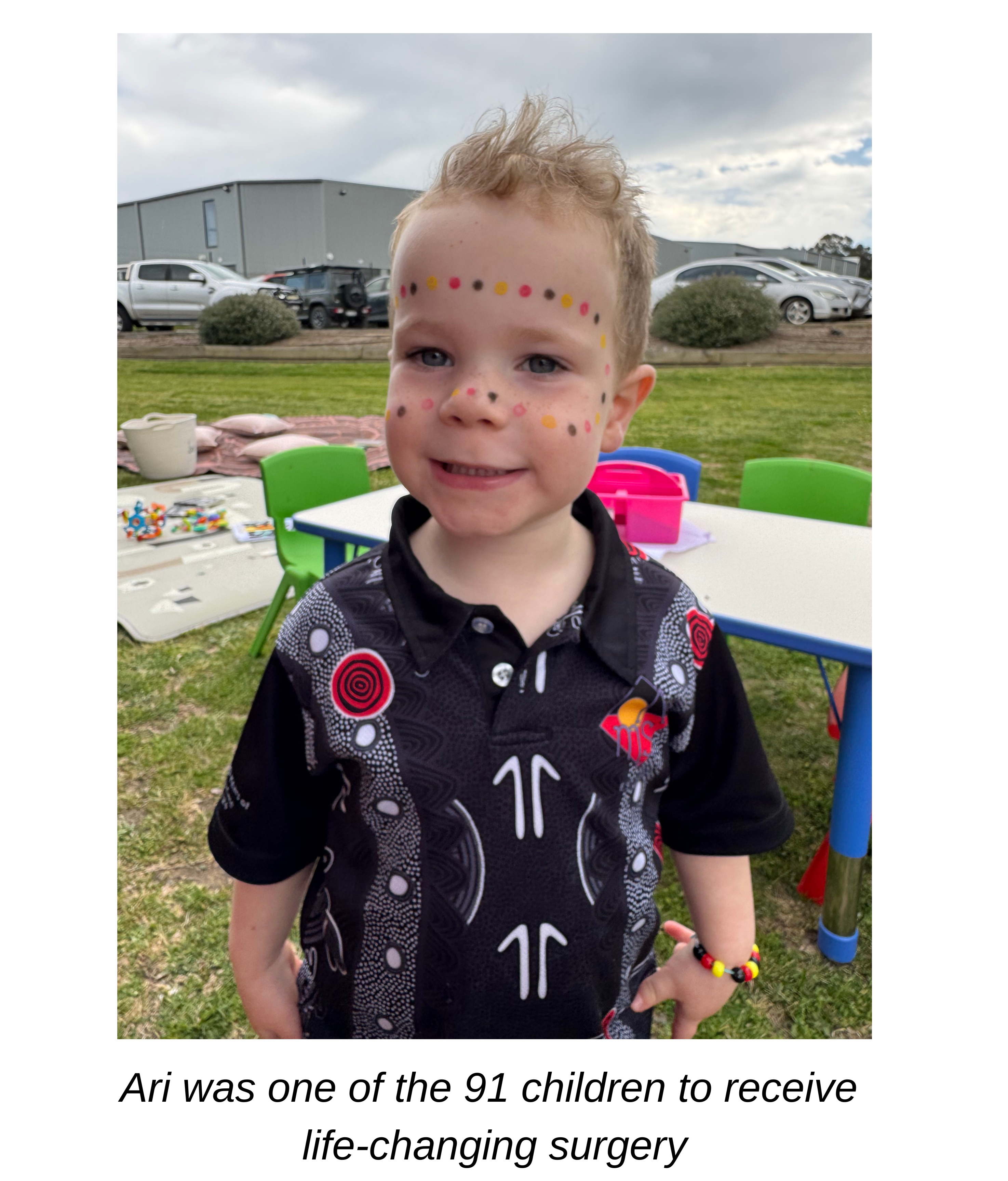 Young boy smiling at the camera with dot face paint