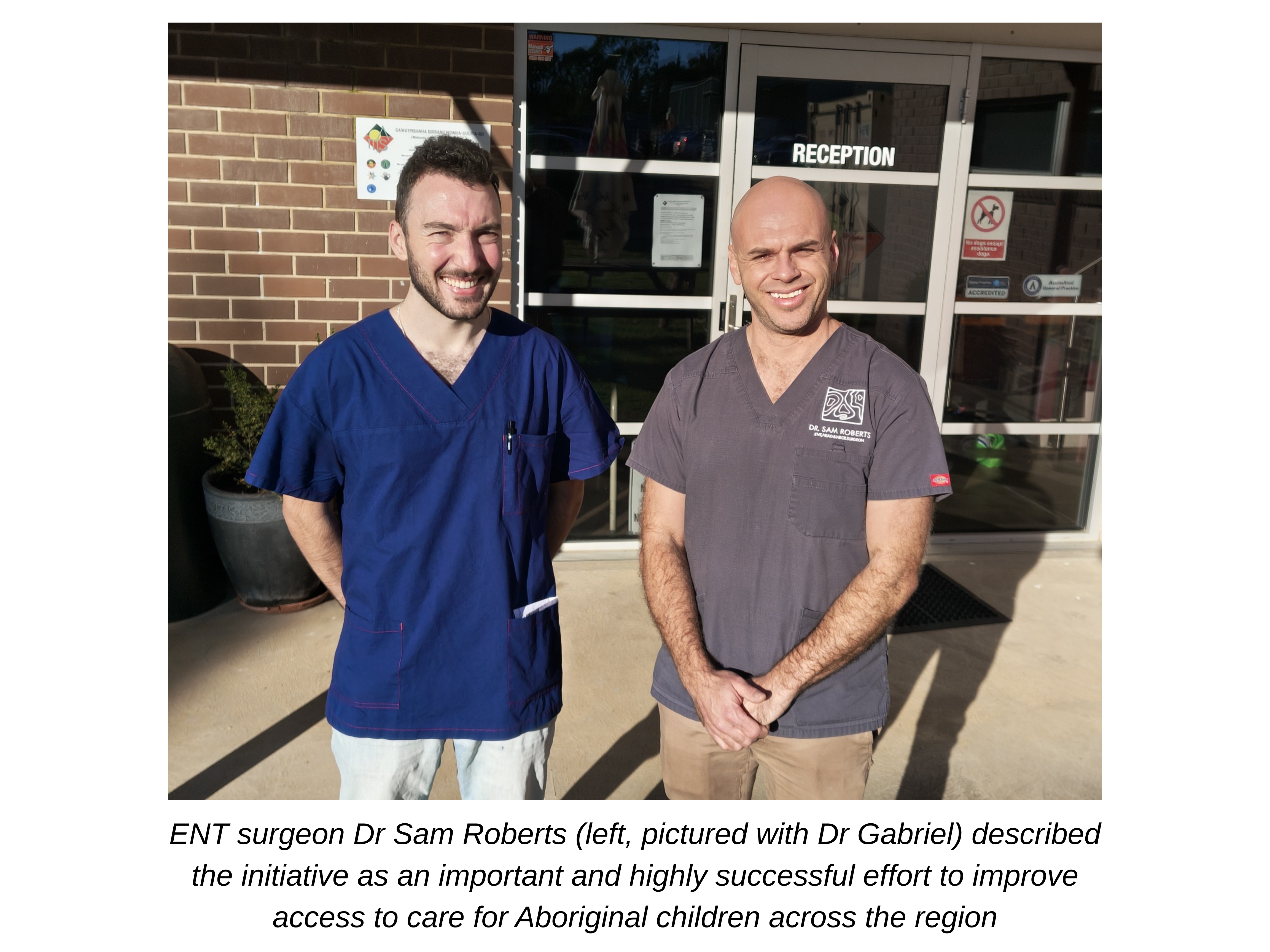 Two males in blue and grey scrubs smiling at the camera
