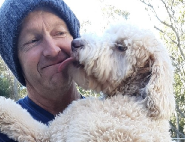 Man in blue beanie holding blonde dog