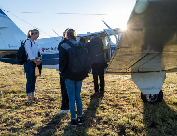 Three people boarding a small plane on grass