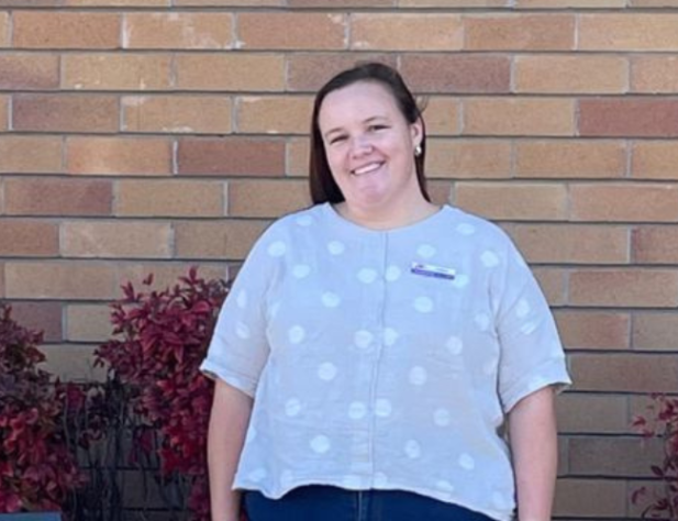 Female standing in front of a brick wall, smiling at the camera